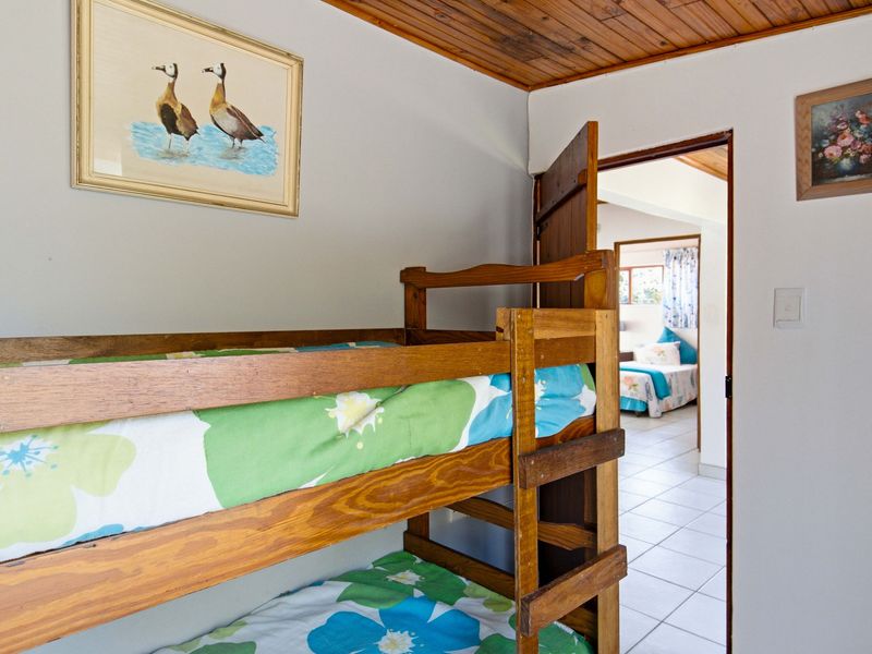 A bedroom featuring a timber tongue and groove ceiling and tiled flooring, with a view through to an adjacent bedroom.