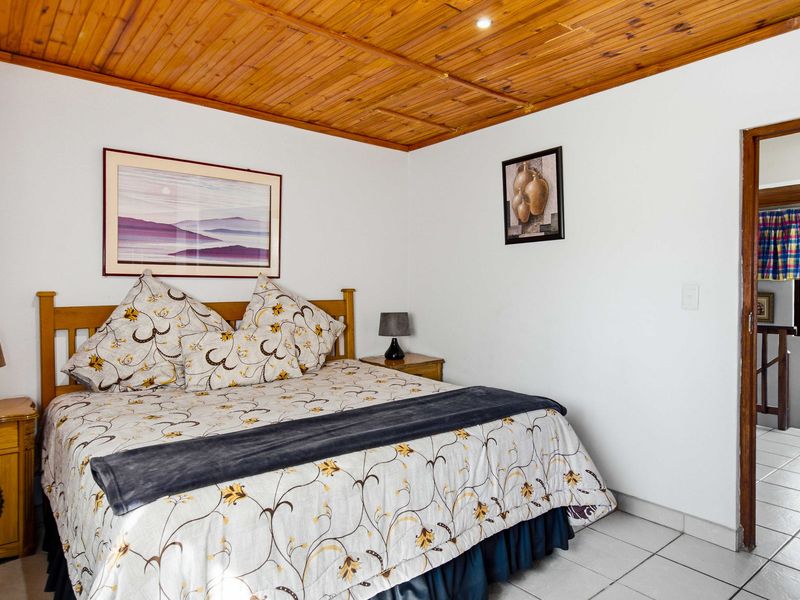 A bedroom featuring a warm timber tongue and groove ceiling, recessed lighting, and neutral ceramic floor tiles.