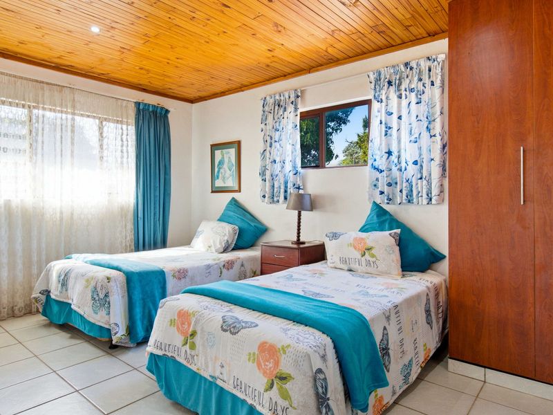 A bedroom featuring a timber-clad ceiling, tiled flooring, and a built-in wardrobe, offering a functional and well-lit space.