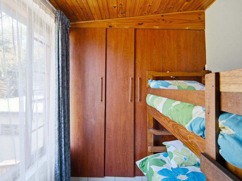 A bedroom featuring built-in wooden cabinetry and a timber tongue and groove ceiling, providing a classic, dated aesthetic.