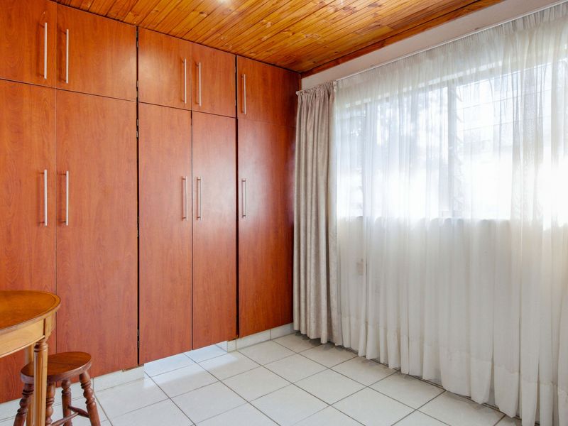 Bedroom featuring extensive built-in wooden cabinetry, tiled flooring, and a timber-clad ceiling, providing ample storage space.