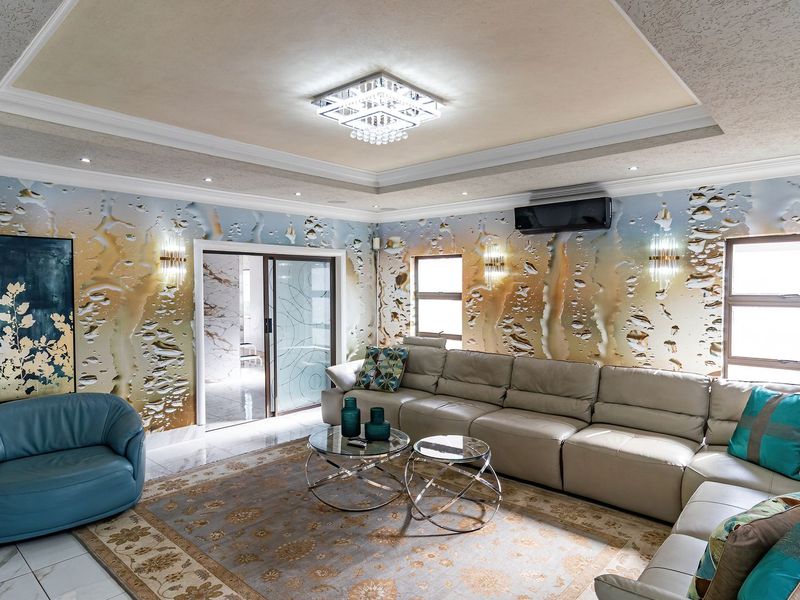 Spacious living room featuring a recessed ceiling with crystal chandelier, split-system air conditioning, and tiled flooring with decorative wall finishes.