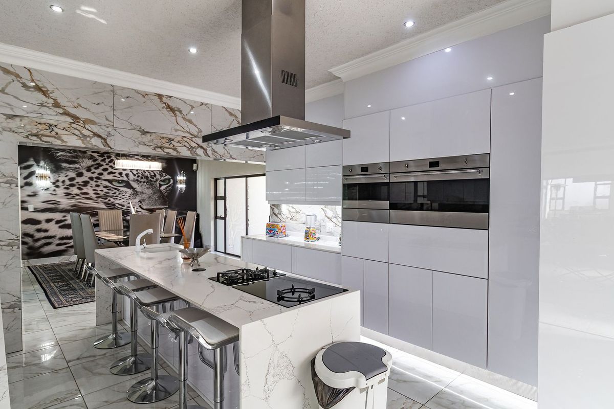 Modern, high-end kitchen featuring a marble-look island, integrated double ovens, sleek cabinetry, and premium finishes throughout.