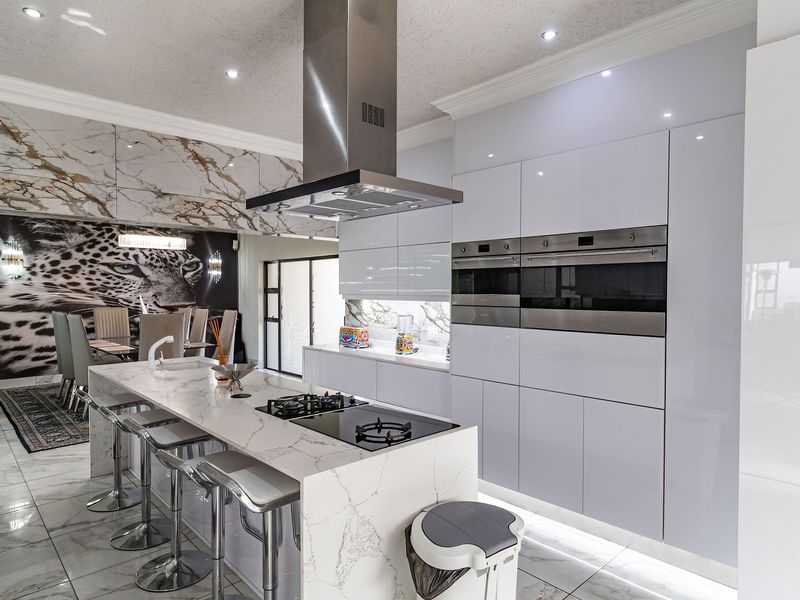 Modern, high-end kitchen featuring a marble-look island, integrated double ovens, sleek cabinetry, and premium finishes throughout.