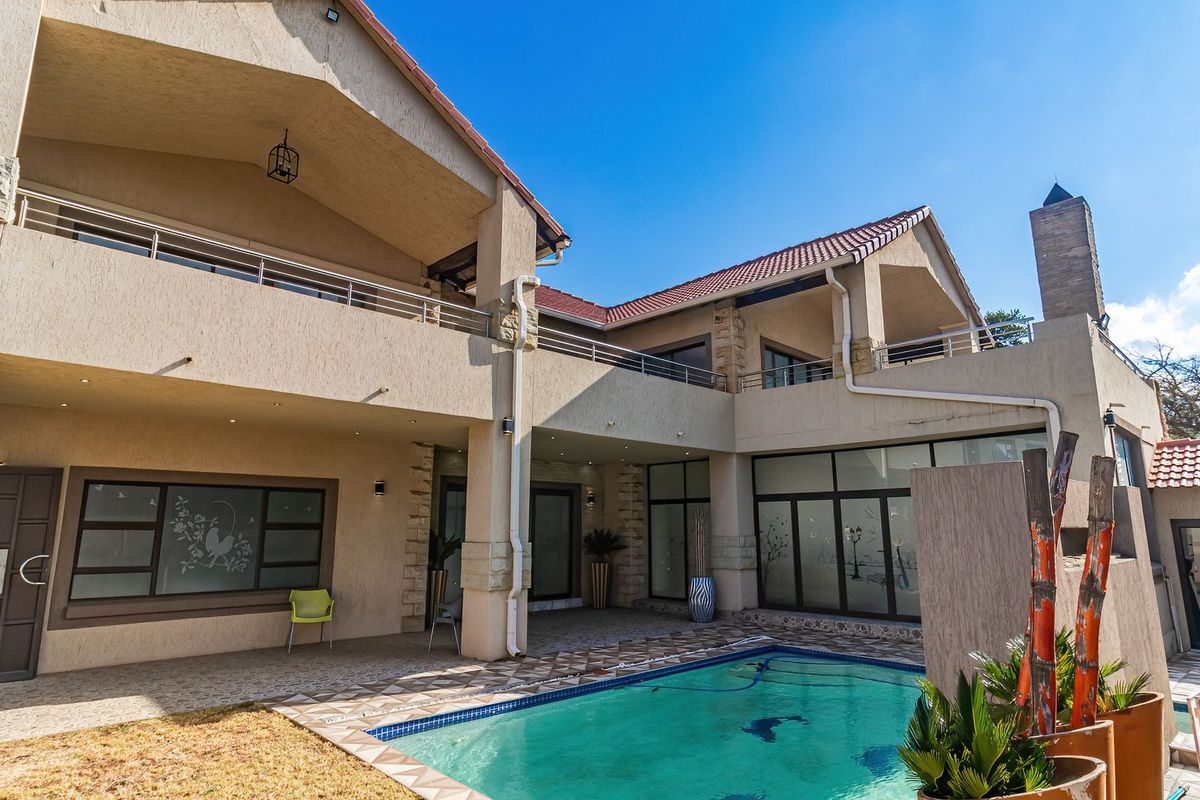 Spacious rear exterior featuring a swimming pool, covered patio, upper-level balconies, and modern architectural finishes with stone accents.