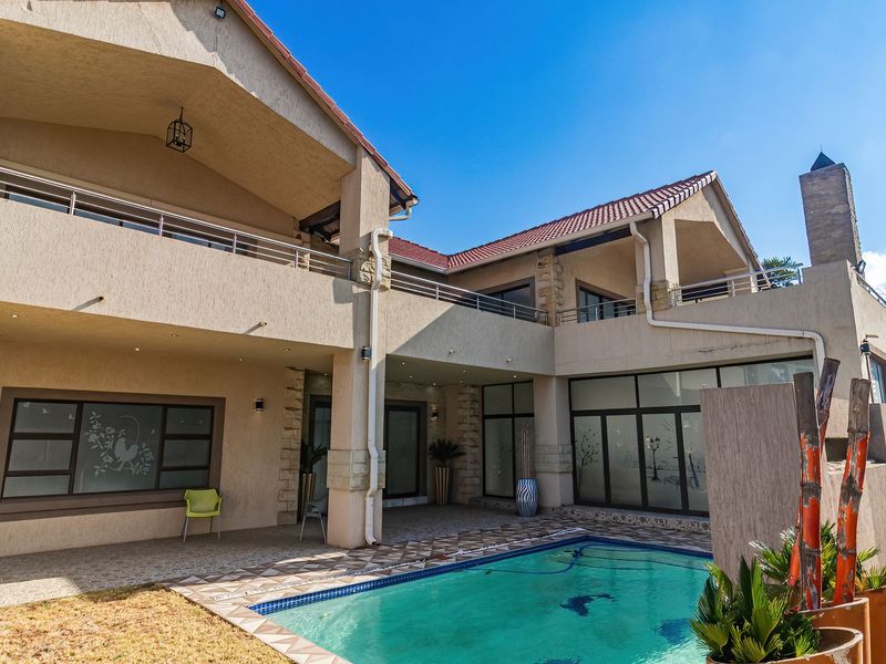 Spacious rear exterior featuring a swimming pool, covered patio, upper-level balconies, and modern architectural finishes with stone accents.