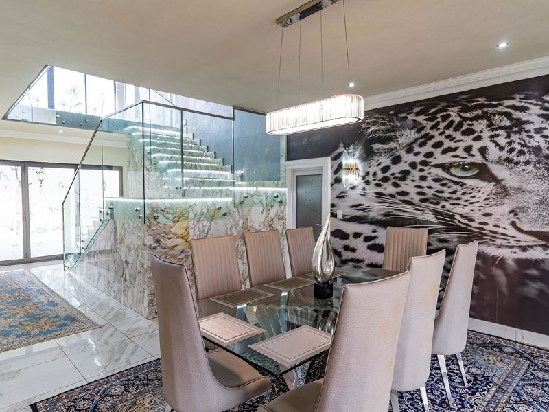 Elegant dining area featuring a striking glass staircase with marble accents, polished tile flooring, and modern pendant lighting.