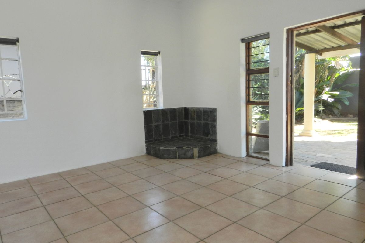 An empty living room featuring tiled flooring, a corner fireplace, and direct access to an outdoor patio area through a sliding door.