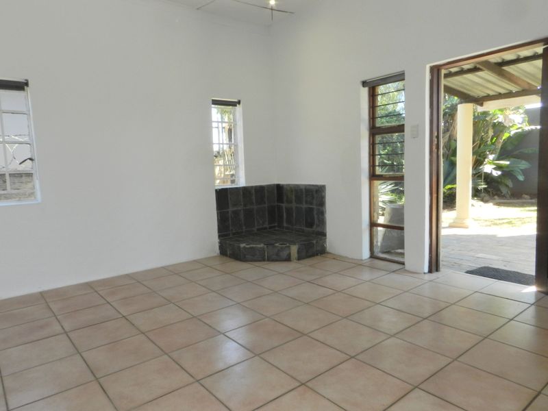 An empty living room featuring tiled flooring, a corner fireplace, and direct access to an outdoor patio area through a sliding door.