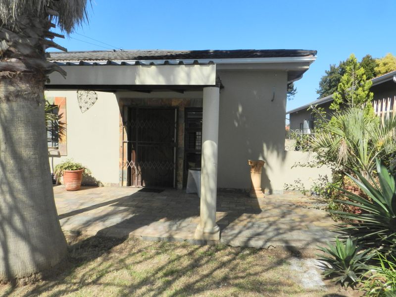 A covered patio area featuring stone paving, a support column, and a secure entrance gate, providing a functional outdoor space.