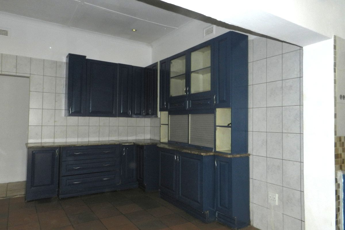A functional kitchen space featuring dark blue built-in cabinetry, stone countertops, and tiled splashbacks, offering a solid foundation for a modern update.