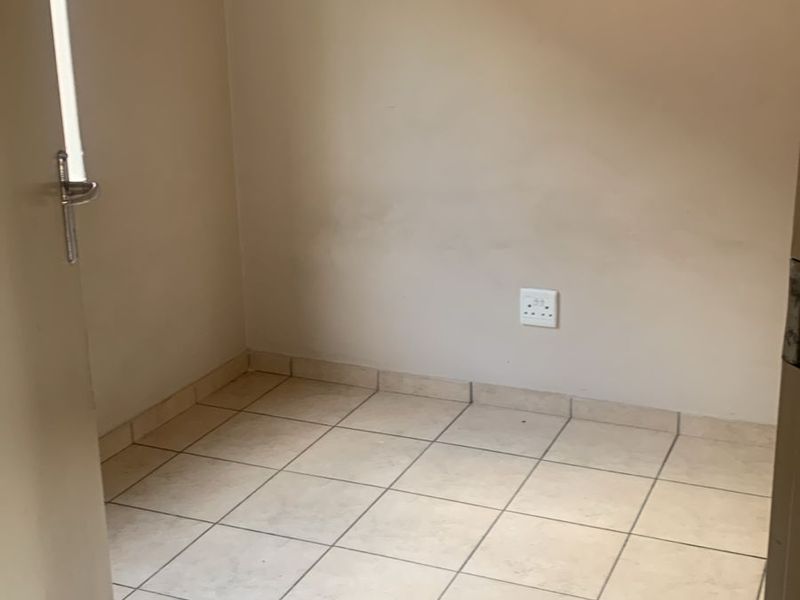 An empty, compact room featuring neutral tiled flooring and plain walls, suitable for use as a small bedroom or home office space.