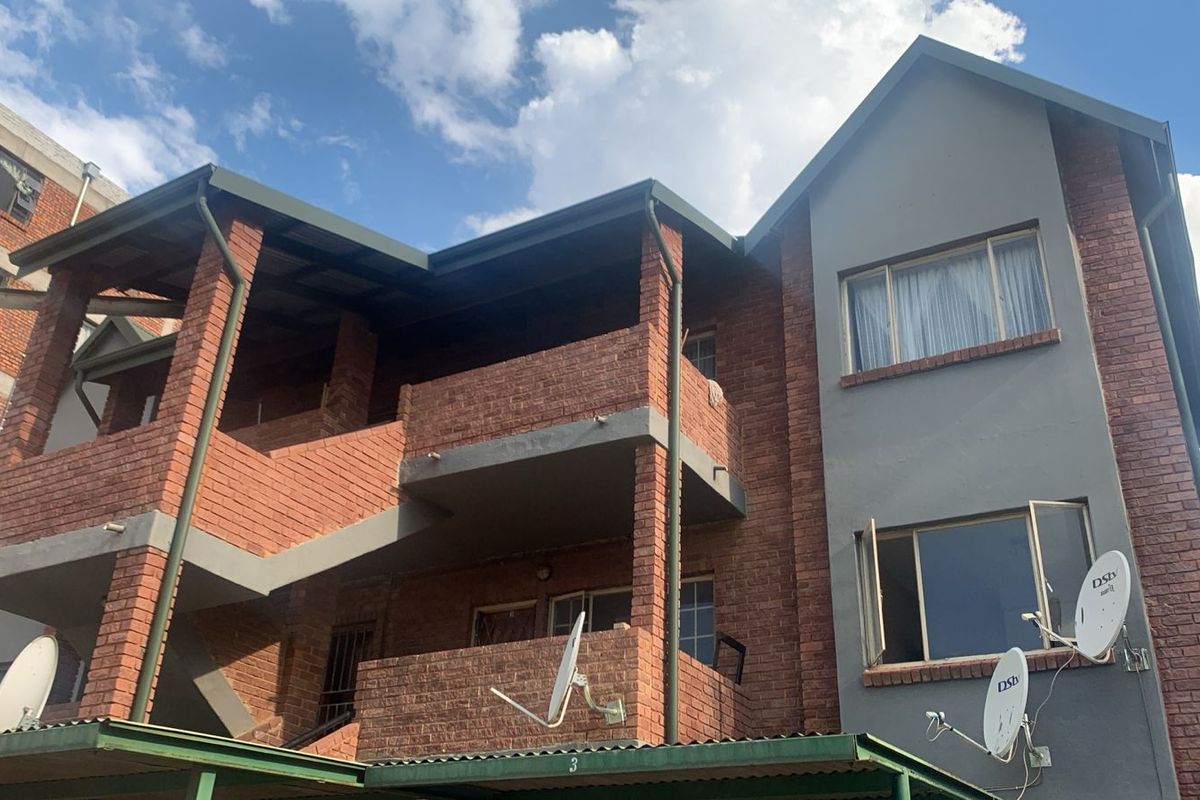 Exterior view of a multi-story apartment building featuring face brick construction, private balconies, and external staircases.