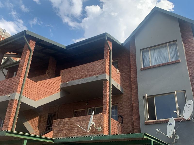 Exterior view of a multi-story apartment building featuring face brick construction, private balconies, and external staircases.
