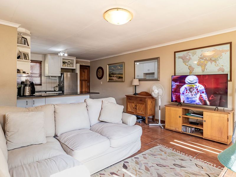 Open-plan living area featuring tiled floors and a connected kitchen space, providing a functional and integrated layout for daily living.