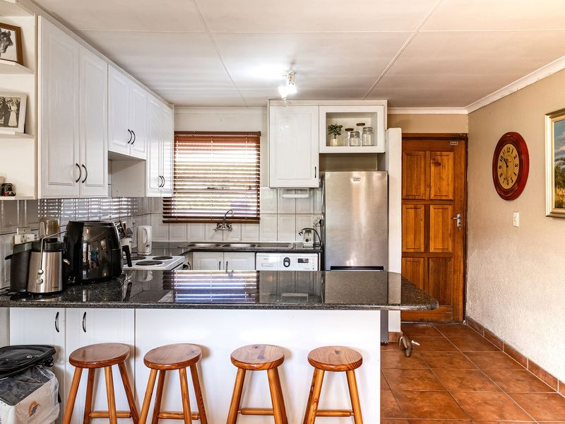 Functional kitchen featuring granite countertops, white cabinetry, a breakfast bar, and tiled flooring, offering a practical layout for daily meal preparation.