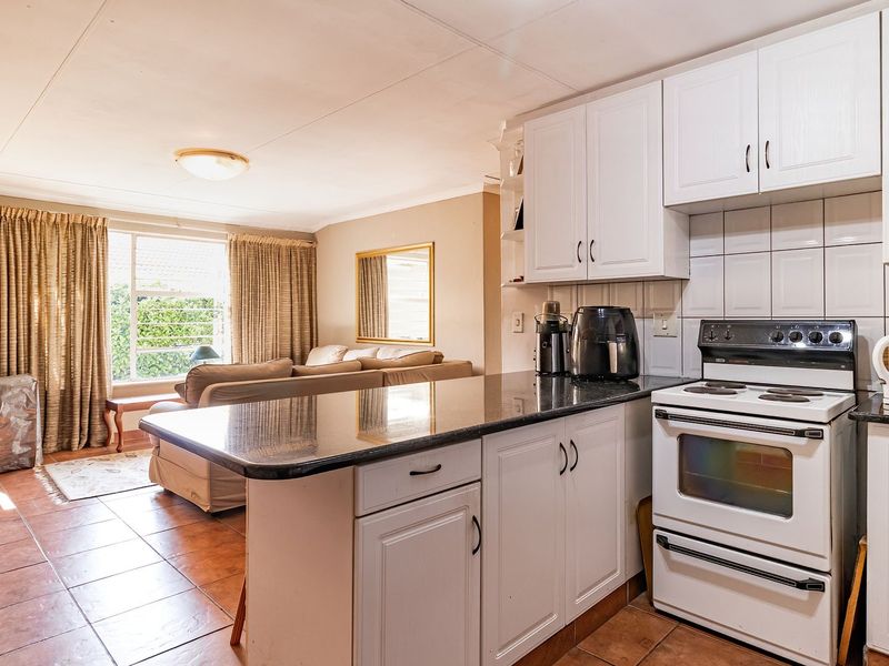 Open-plan kitchen and living area featuring granite countertops, white cabinetry, and direct access to an outdoor patio through sliding glass doors.