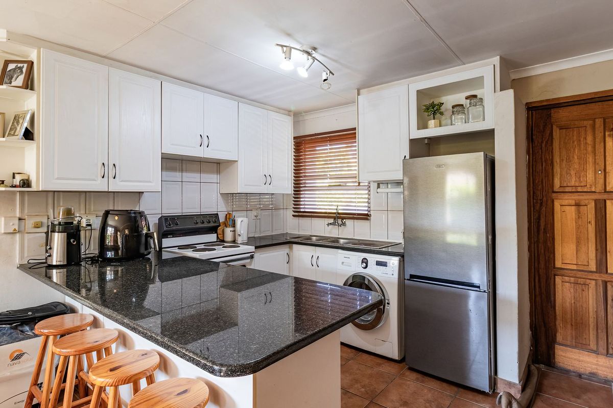 Functional kitchen featuring granite countertops, built-in cabinetry, electric stove, and integrated laundry plumbing, offering a practical layout for daily meal preparation.