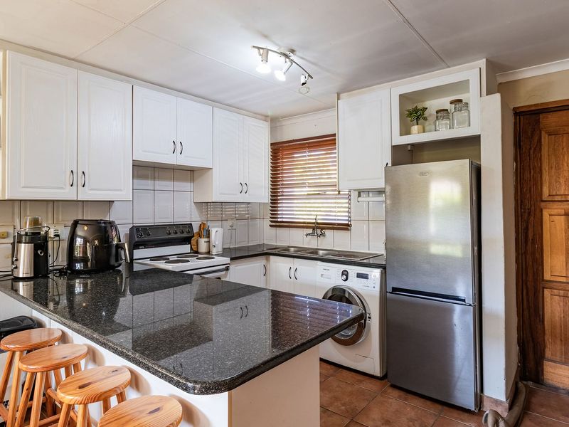 Functional kitchen featuring granite countertops, built-in cabinetry, electric stove, and integrated laundry plumbing, offering a practical layout for daily meal preparation.