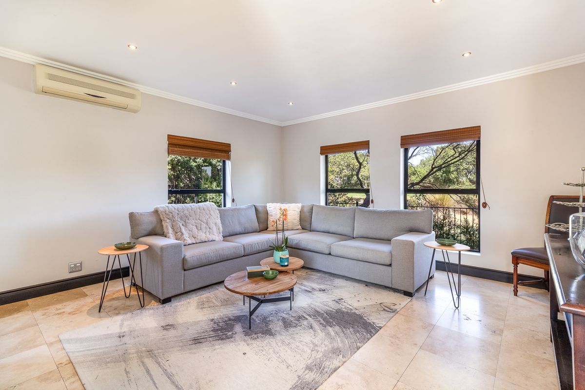 A bright and well-maintained living room featuring tiled flooring, recessed downlighting, and a wall-mounted split-system air conditioner.