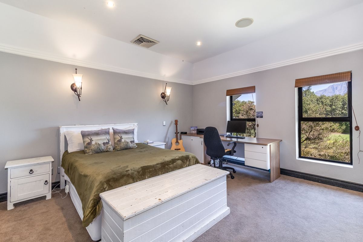 Spacious bedroom featuring neutral wall tones, crown molding, recessed lighting, and large windows with scenic views.