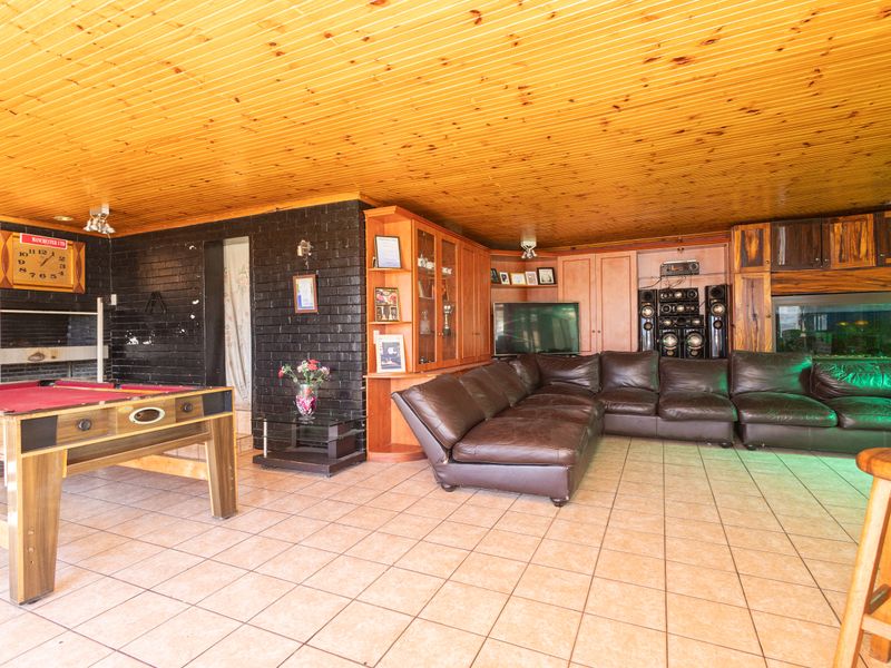 Spacious living area featuring a timber tongue and groove ceiling, tiled flooring, and built-in cabinetry, offering a versatile space for relaxation and entertainment.