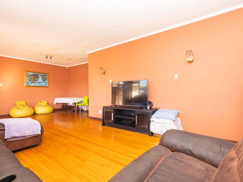 Spacious living room featuring hardwood flooring and wall sconces, requiring ceiling repairs and cosmetic updates to improve the overall aesthetic.