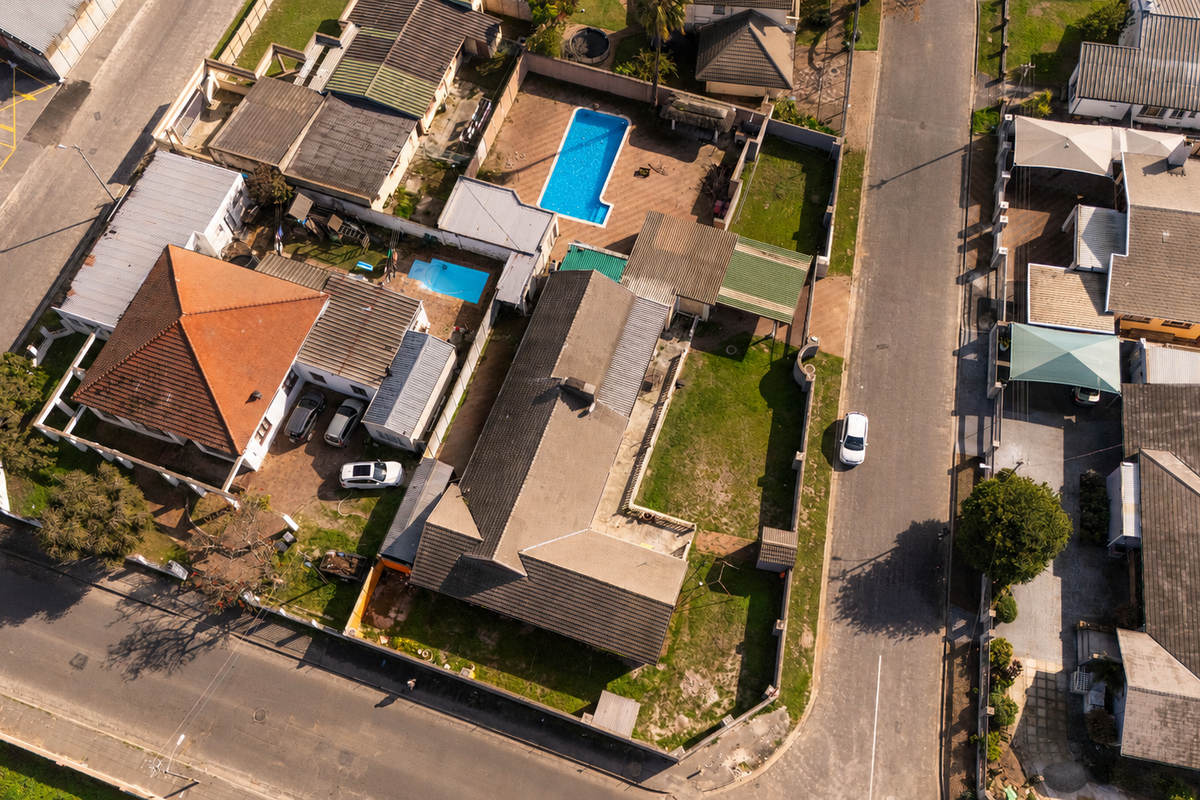 Aerial view of the property showing the main house, swimming pool, garden areas, and surrounding neighborhood layout.