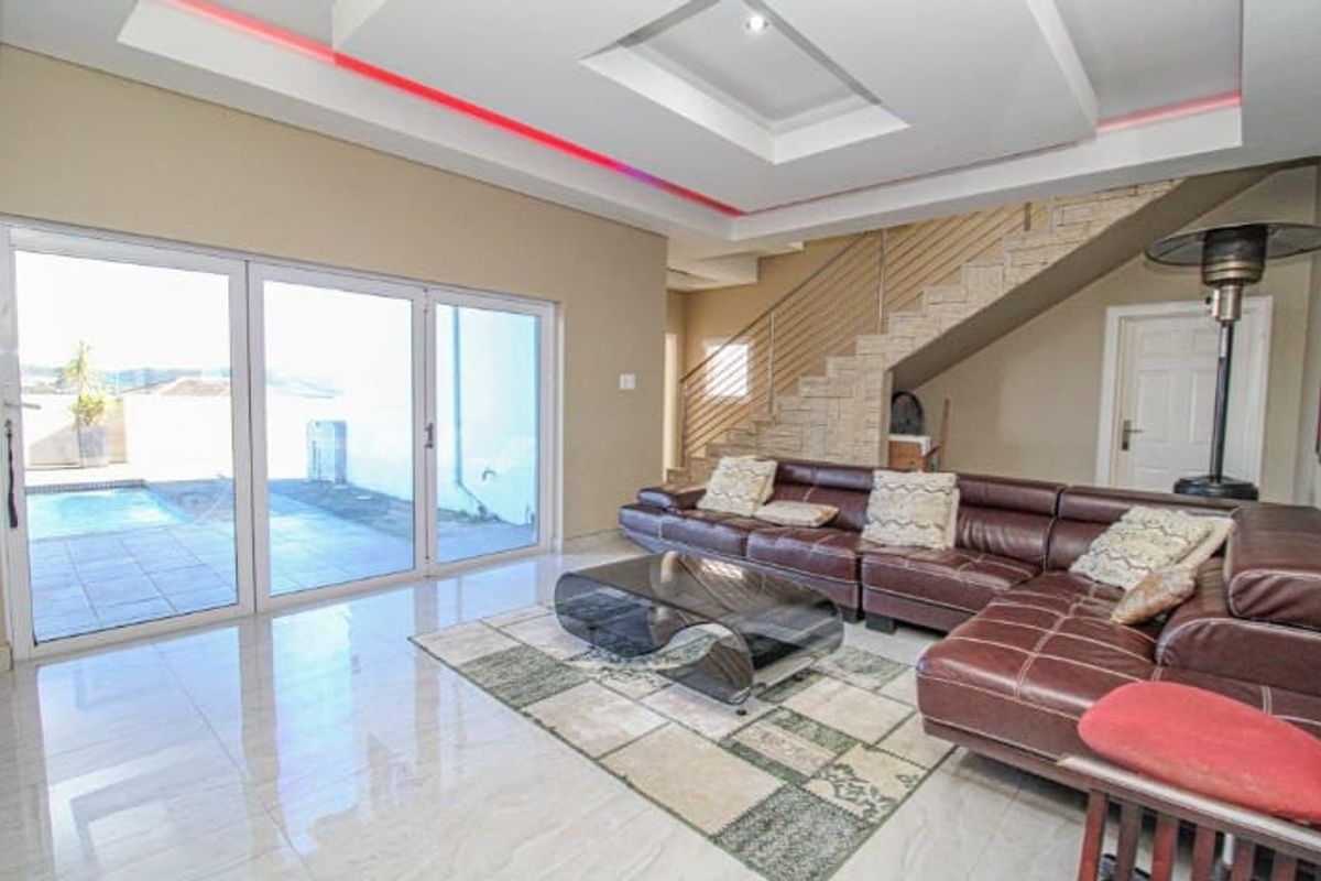 Spacious living room featuring modern recessed ceiling lighting, polished tile floors, and large sliding doors providing direct access to the outdoor pool area.