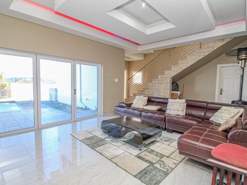 Spacious living room featuring modern recessed ceiling lighting, polished tile floors, and large sliding doors providing direct access to the outdoor pool area.
