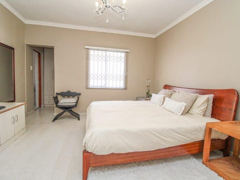 A well-maintained bedroom featuring neutral wall tones, built-in storage, and security bars on the window, providing a comfortable and functional living space.