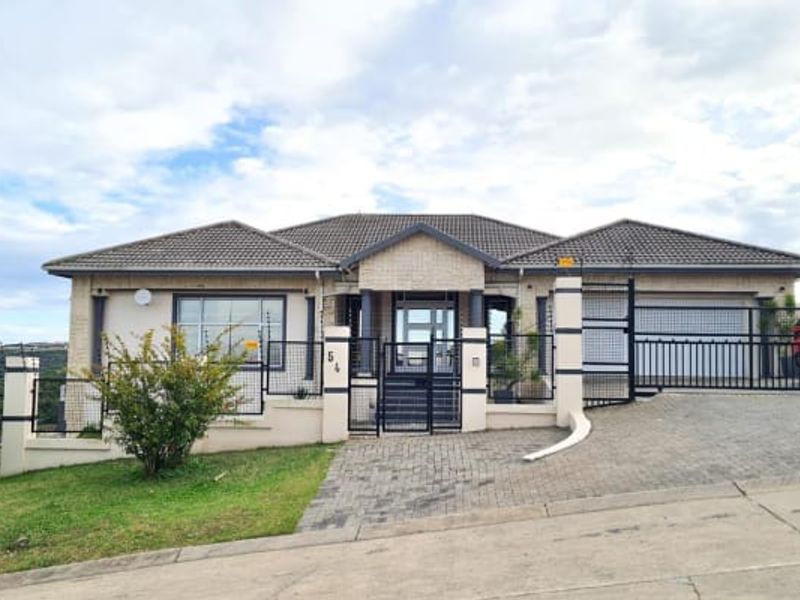 Front elevation of a well-maintained single-story house featuring a tiled roof, brick facade, paved driveway, and secure gated entrance.