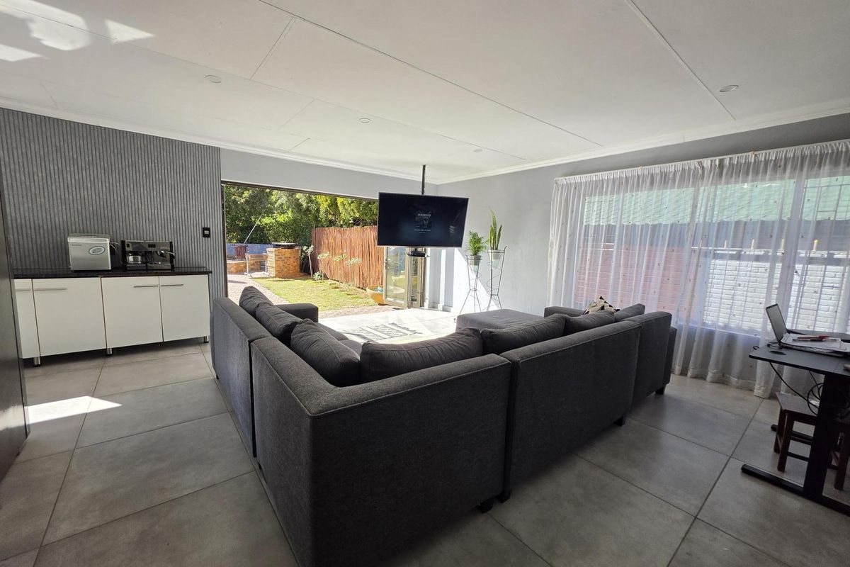 Spacious living area featuring large format floor tiles, recessed lighting, and seamless access to the rear garden through sliding glass doors.
