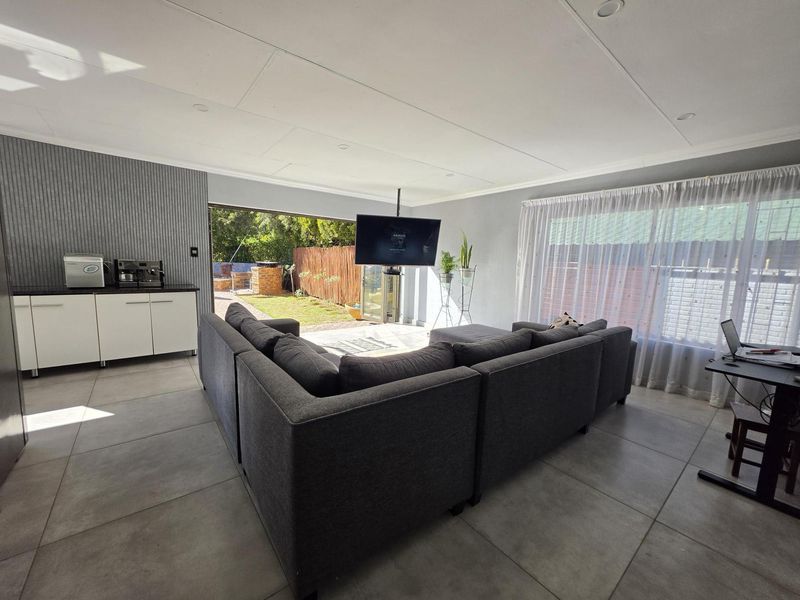 Spacious living area featuring large format floor tiles, recessed lighting, and seamless access to the rear garden through sliding glass doors.