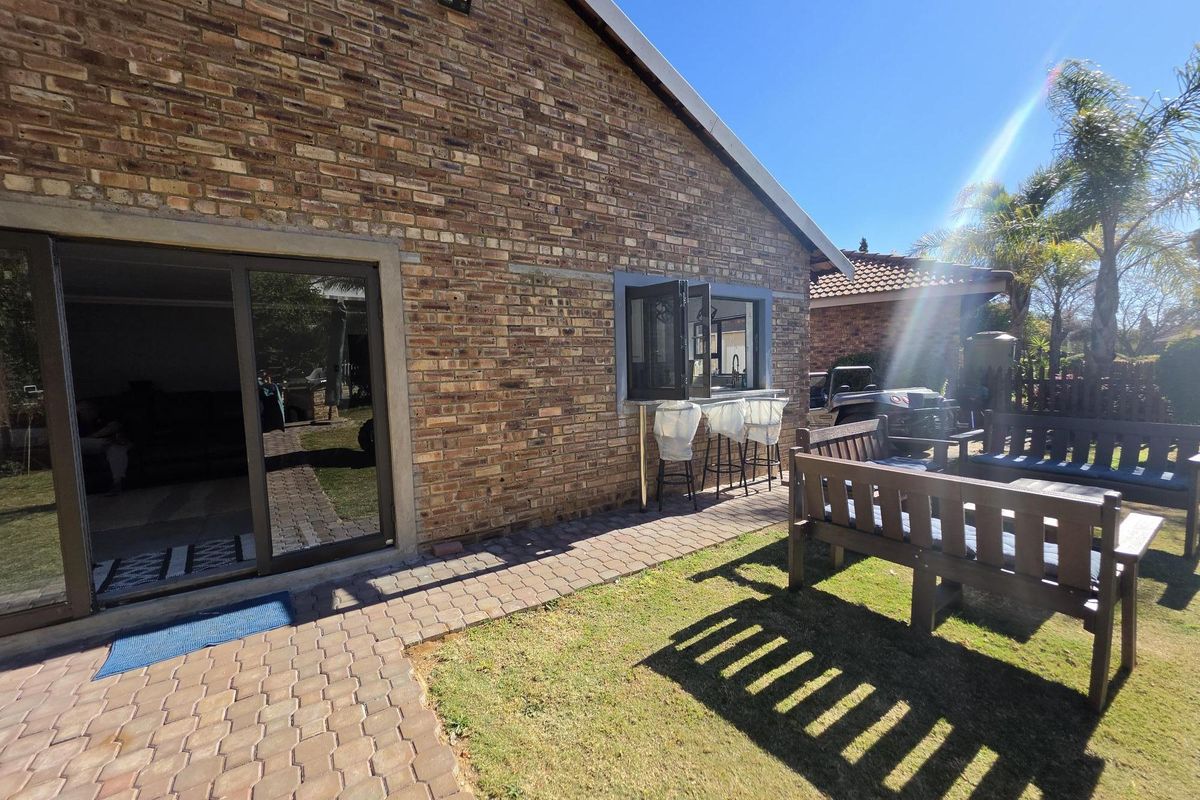 Rear exterior view featuring a brick facade, paved walkway, and a convenient pass-through window connecting to the interior living space.