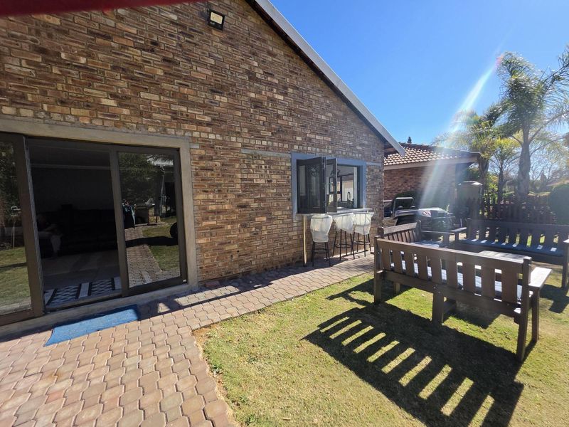 Rear exterior view featuring a brick facade, paved walkway, and a convenient pass-through window connecting to the interior living space.
