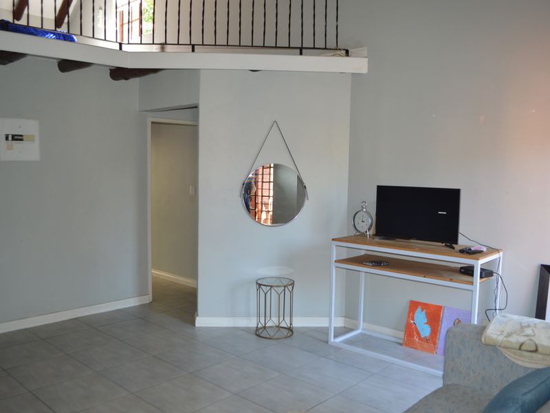 Living area featuring tiled flooring and a mezzanine level with a wrought iron balustrade, providing an open and airy feel to the apartment.