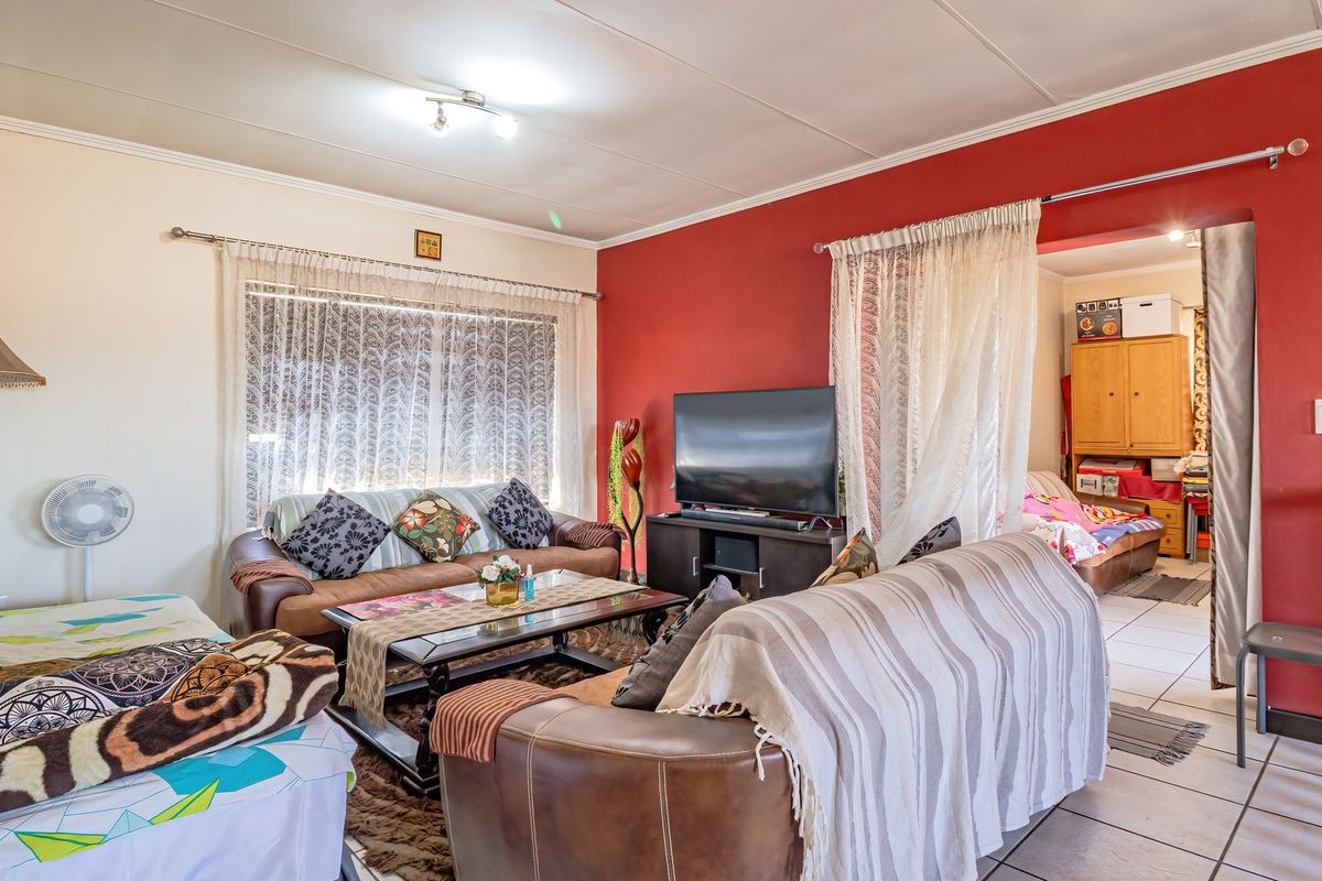 A living room area featuring tiled flooring and a red accent wall, providing a functional space with potential for modernization.