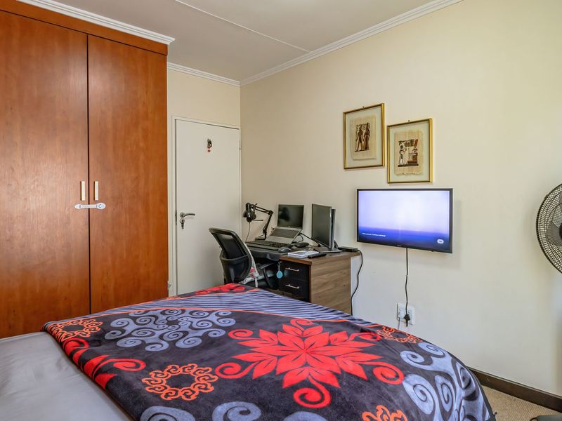 A functional bedroom featuring a large built-in wooden wardrobe, neutral wall finishes, and classic coving detail.