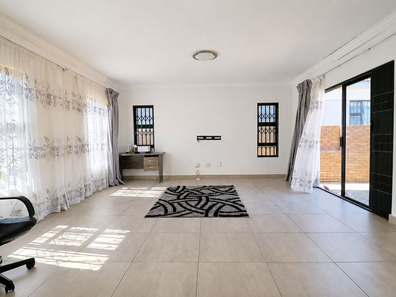 Spacious living area featuring neutral tiled flooring, large windows with natural light, and sliding glass doors providing access to the exterior.