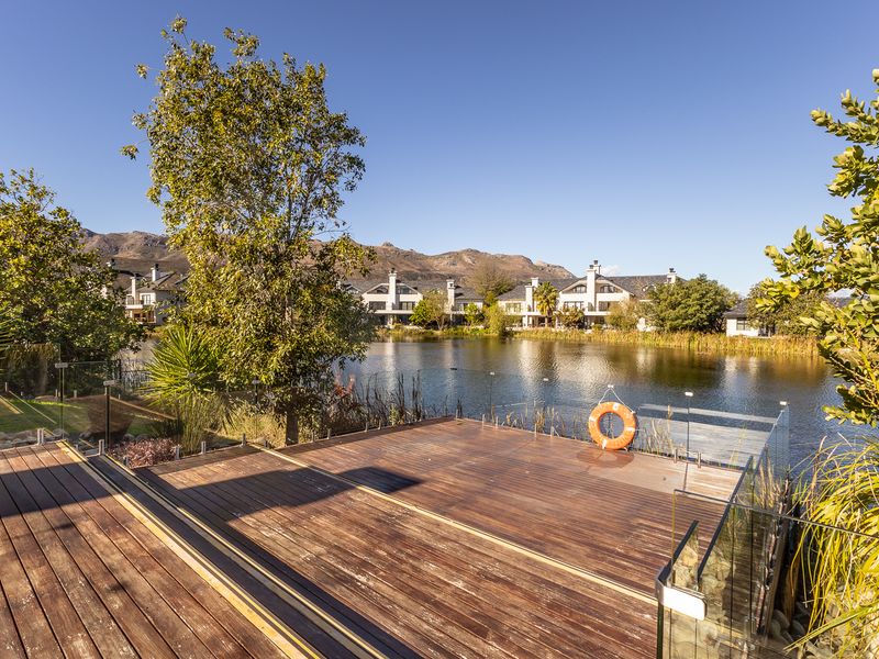 A spacious timber deck overlooking a tranquil lake, featuring a modern glass balustrade and direct water access.