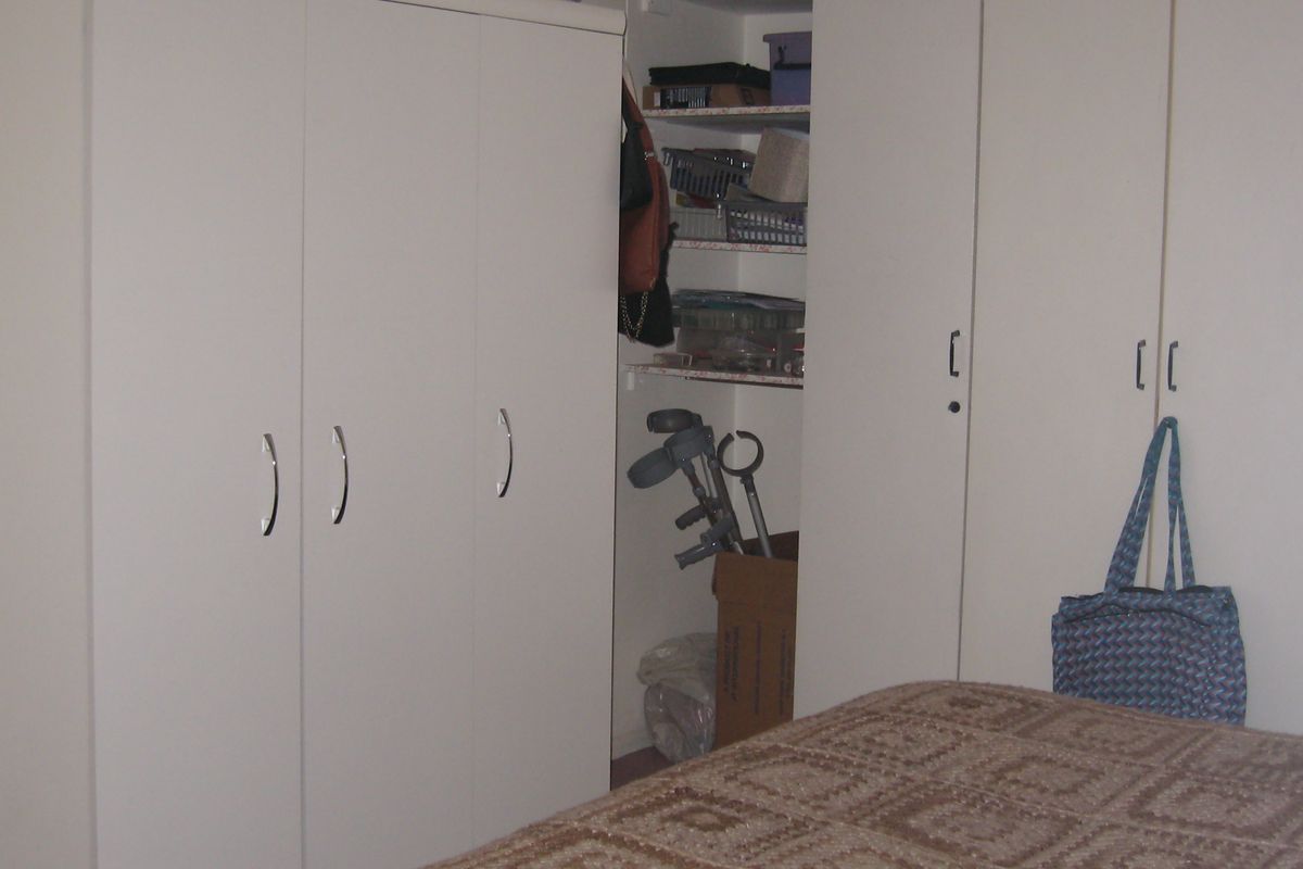Bedroom featuring extensive white built-in cupboards and integrated open shelving for storage.