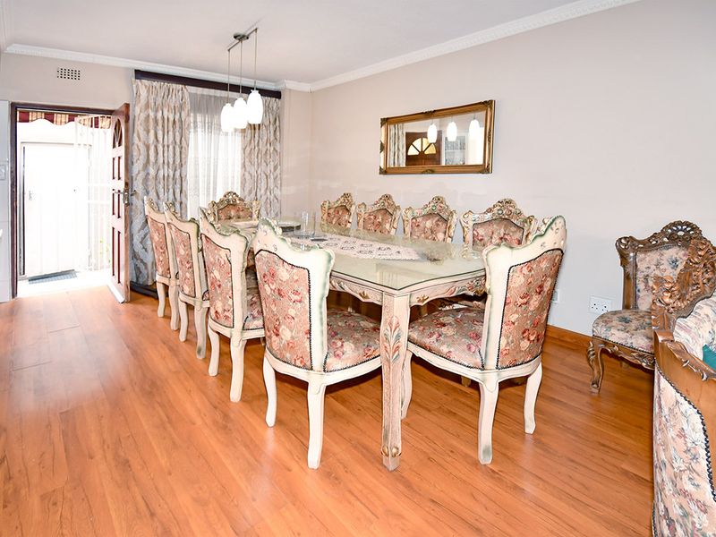 A dining room featuring laminate flooring, decorative cove cornicing, and pendant lighting, with direct access to an exterior area.
