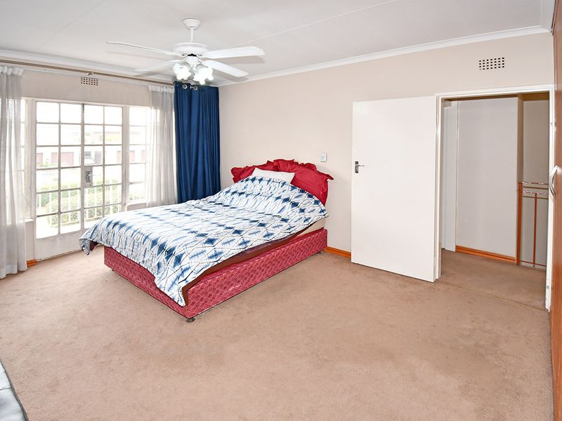 Spacious bedroom featuring built-in cupboards, carpet flooring, a ceiling fan, and direct access to an outdoor area through glass french doors.