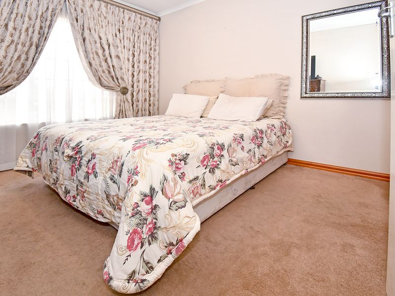 A carpeted bedroom featuring neutral wall finishes, curtain rails, and skirting boards, providing a functional and comfortable sleeping space.