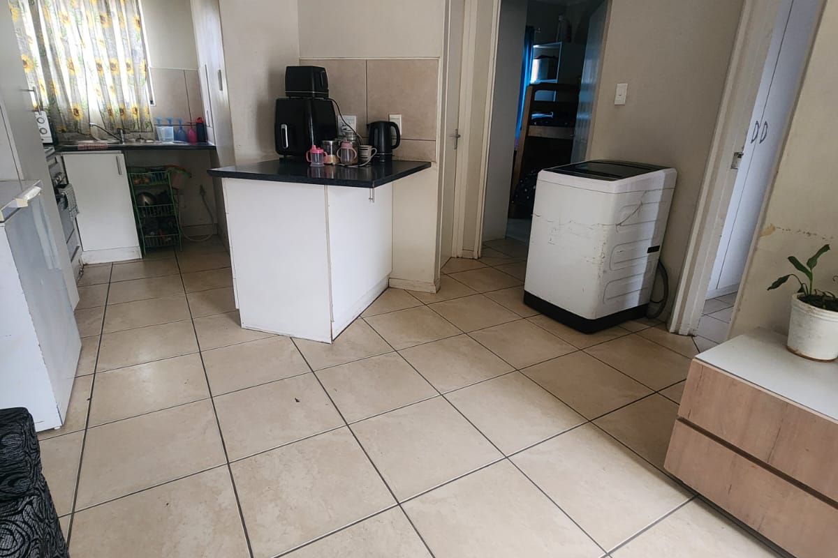 A functional kitchen area featuring tiled flooring, built-in cabinetry, and countertops, requiring some cosmetic updates to improve the overall aesthetic and condition.