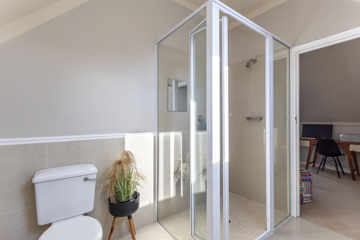 A clean, functional bathroom featuring a glass-enclosed shower, tiled walls, and a standard toilet, with neutral finishes throughout.
