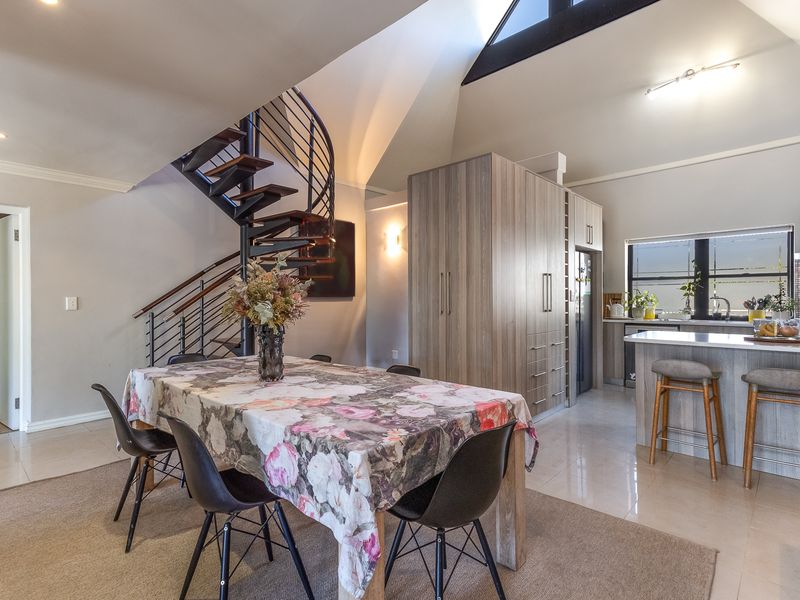 Open-plan living and kitchen area featuring a striking spiral staircase, vaulted ceilings with skylights, modern built-in cabinetry, and a functional kitchen island.