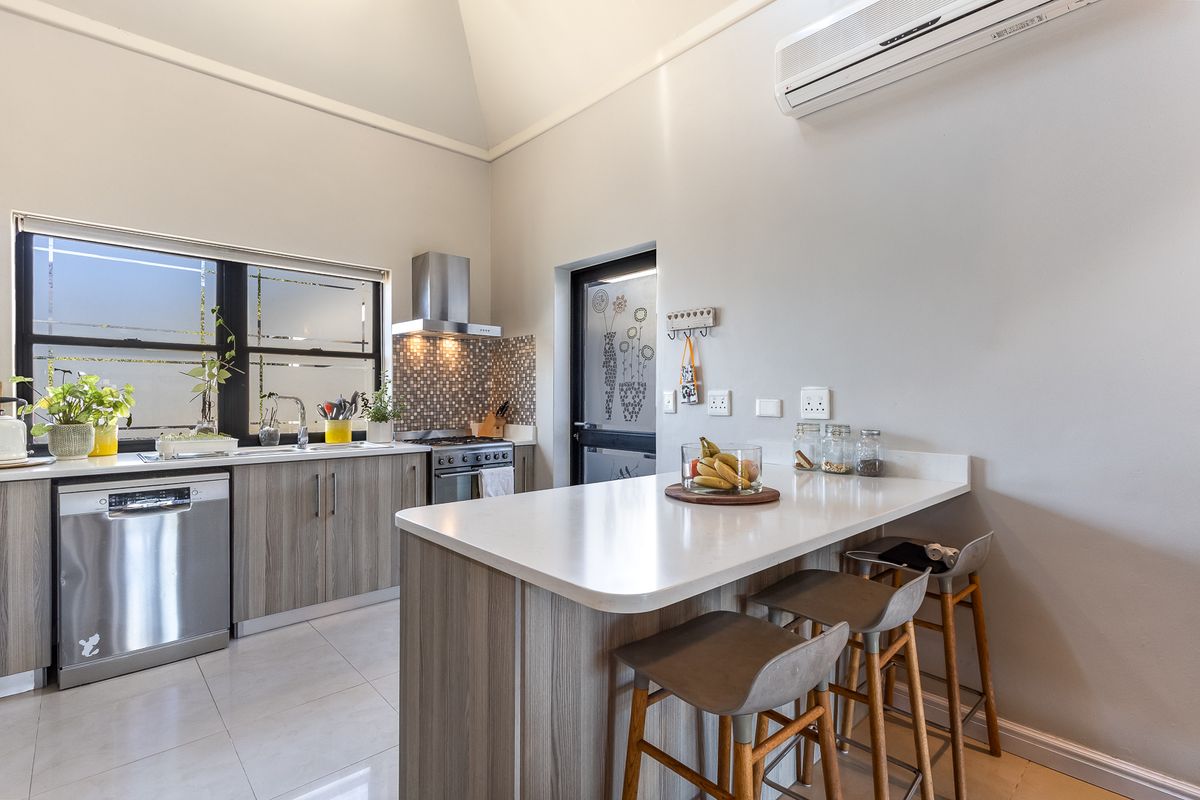 Modern kitchen featuring a central island with breakfast bar, quartz countertops, stainless steel appliances, tiled backsplash, and split-system air conditioning.