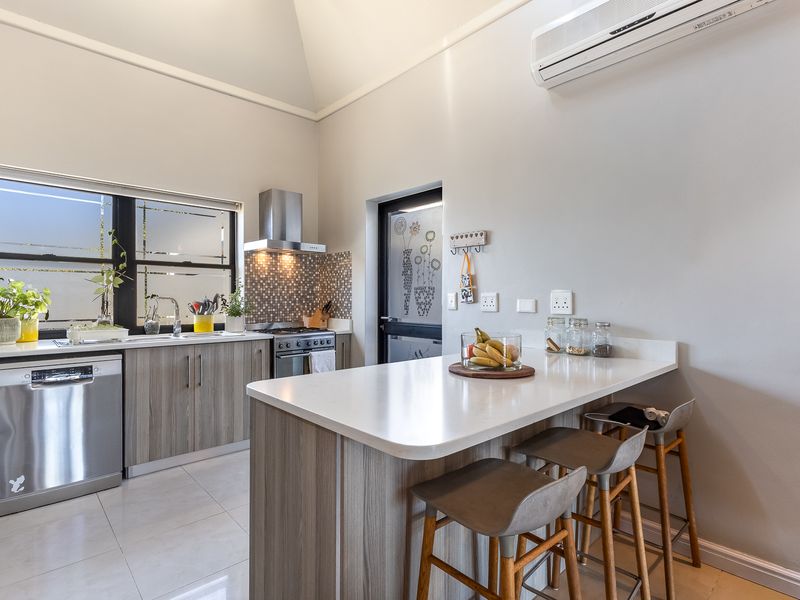 Modern kitchen featuring a central island with breakfast bar, quartz countertops, stainless steel appliances, tiled backsplash, and split-system air conditioning.